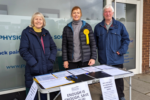Trudi Cotton, Dianne Conduit, and Cllr Tim Dumper standing at a table with papers and a sign reading 'Enough is enough, save our bus!'